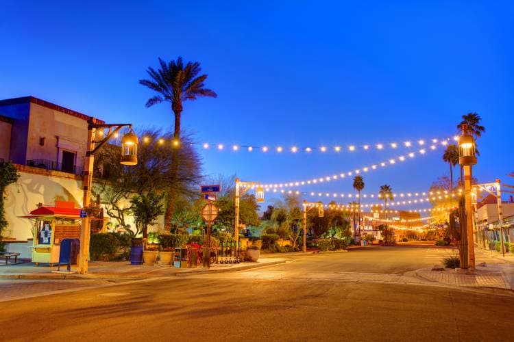 Old Town Scottsdale at night with string lights glowing above the street, palm trees, and vibrant restaurant and bar scene